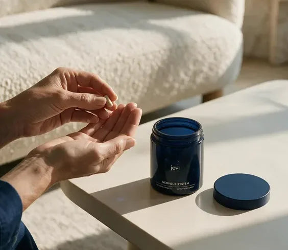 Two capsules tipped into a hand beside an open jar of Jevi Nervous System