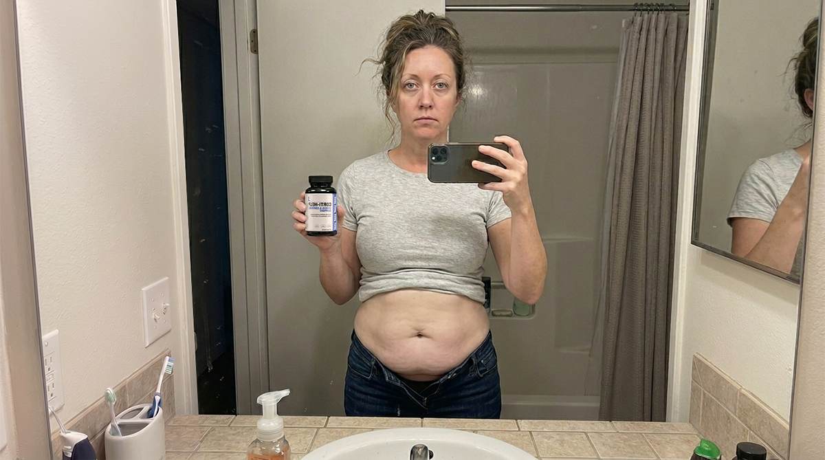Woman checking her weight on a scale during her wellness journey